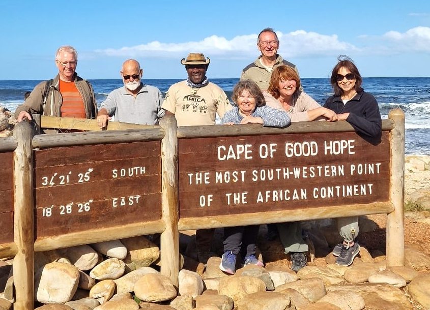 Group smiling at Cape Agulhas on an African Overland Tour