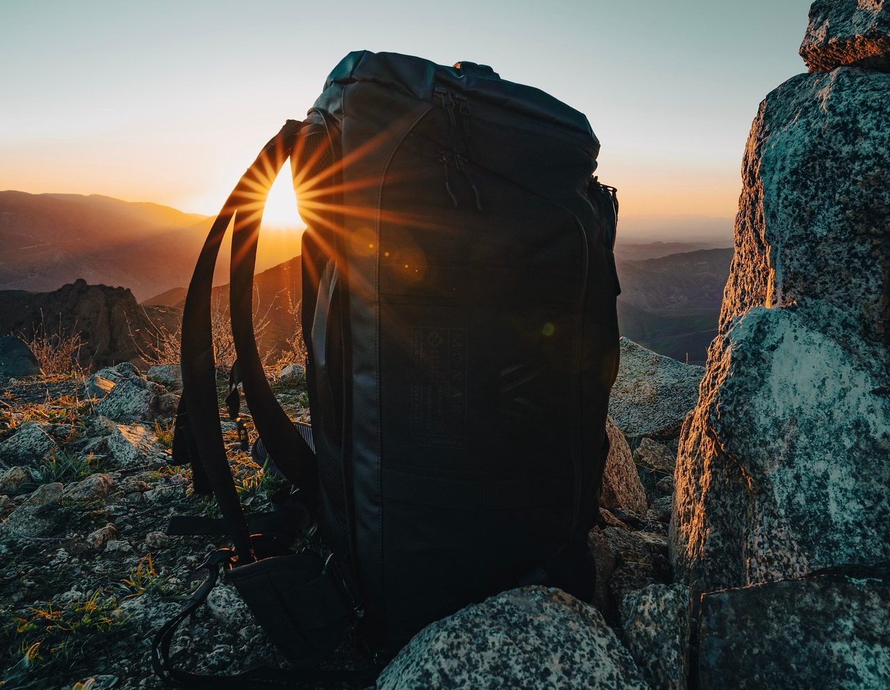 Backpack on rocks backlit by sunrise, African overland safari packing list