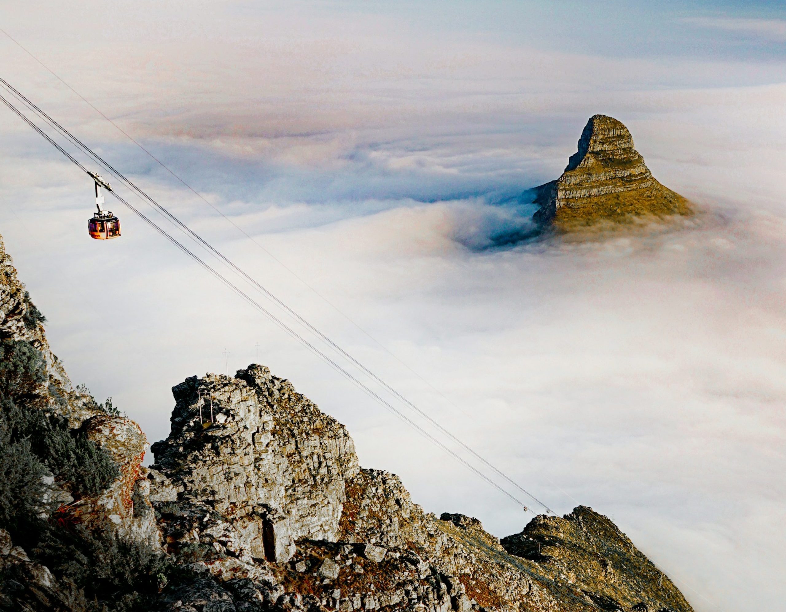 Cable car and Lion's Head seen from atop Table Mountain with lots of mist hiding the city Cable car and Lion's Head seen from atop Table Mountain with lots of mist hiding the city