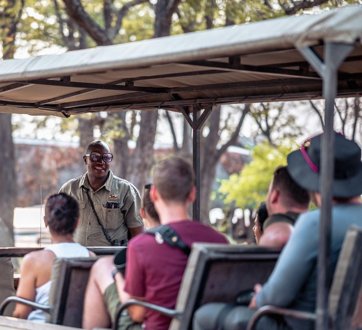 Guide talking to safarigoers in open-sided safari vehicle