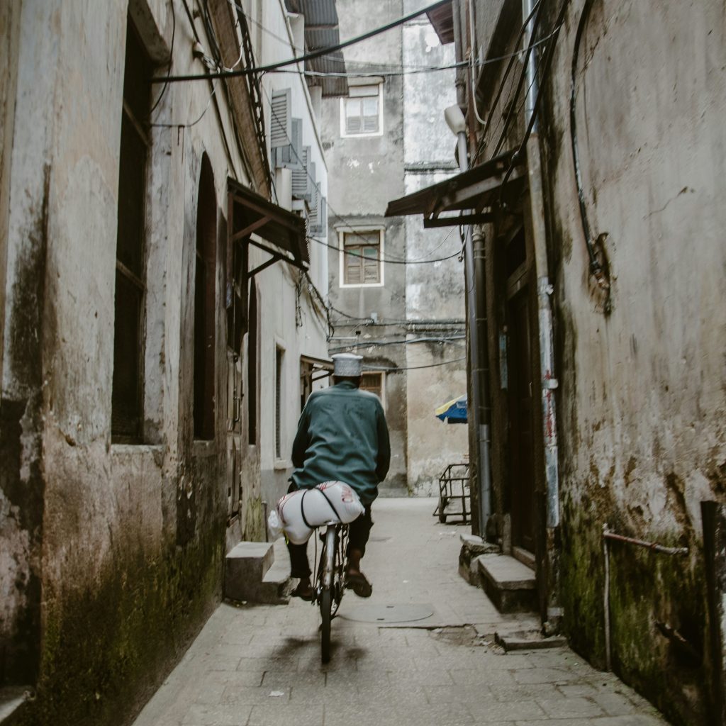 Man cycling through alley in Stone Town, Zanzibar Island