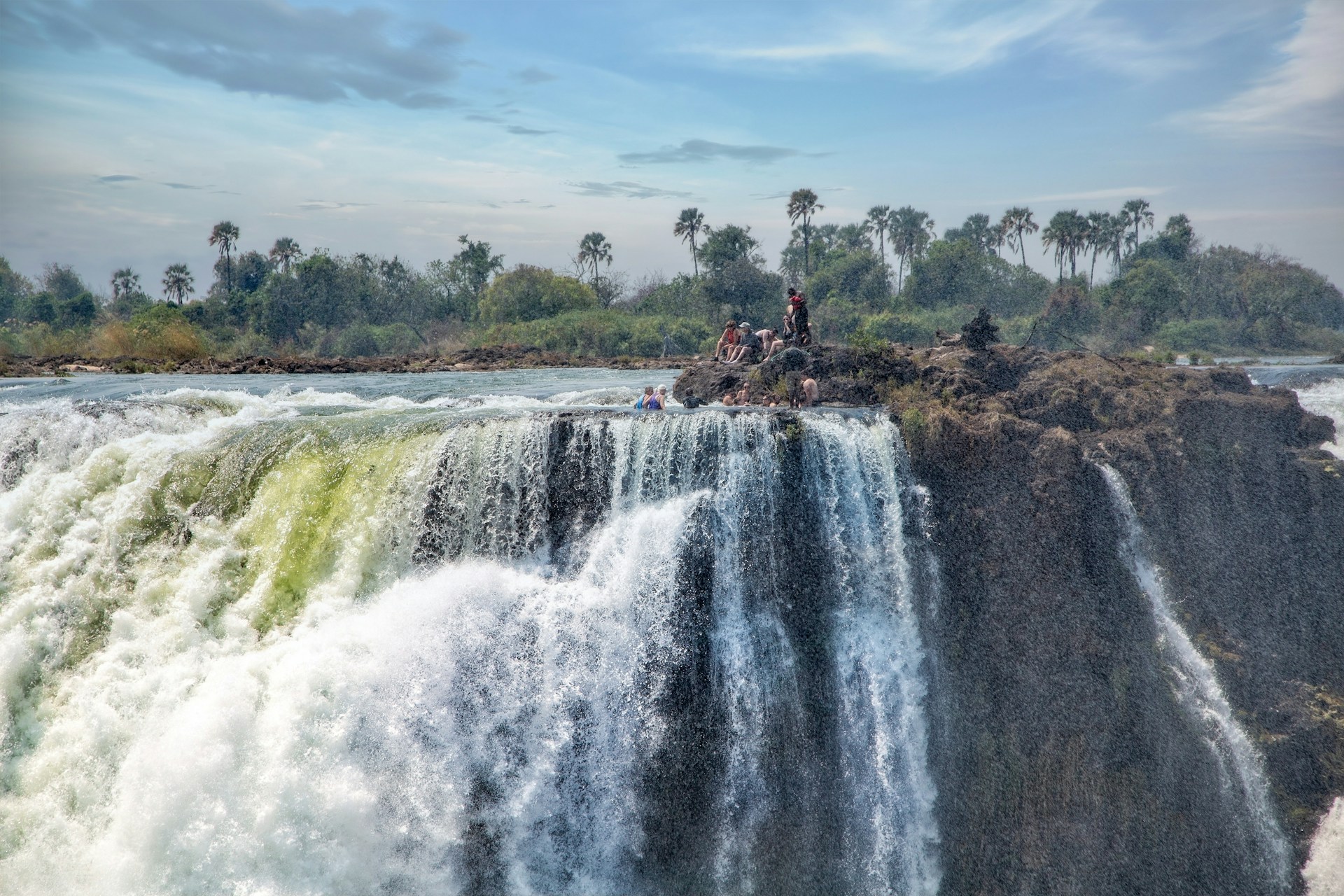 People sitting on rocks at top Victoria Falls