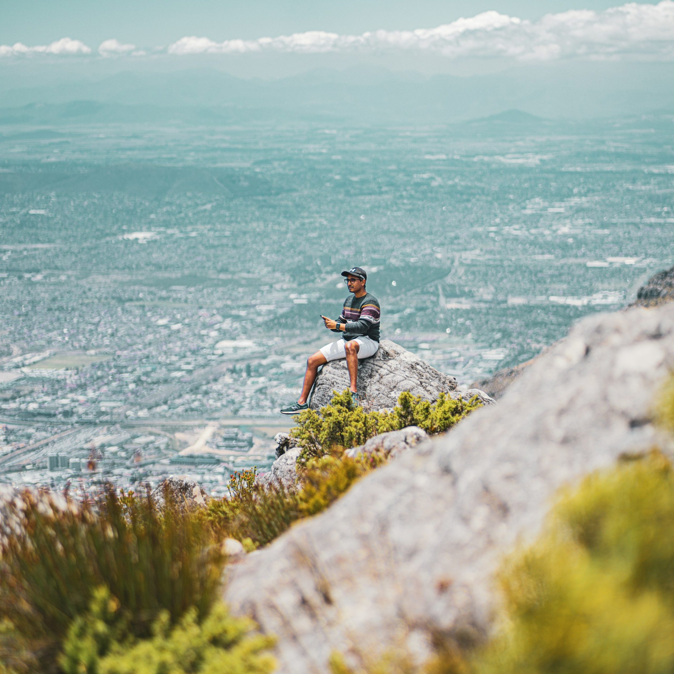 Man sitting on rockyoutcrop on Signal Hill with lazy Cape Town city in background, best photography spots of Cape Town