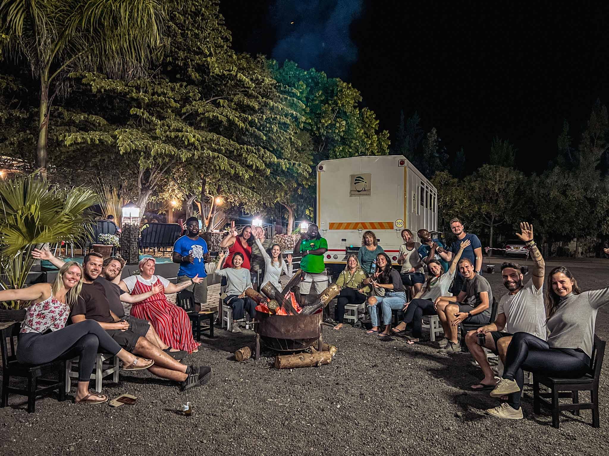 AOT safari truck and group sitting round fire at night