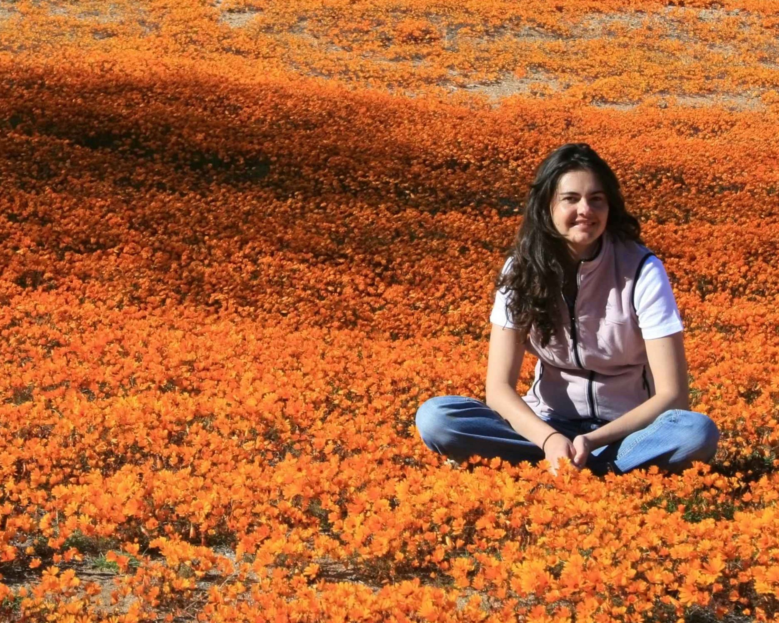 Young woman seated among orange flowers of Namaqualand