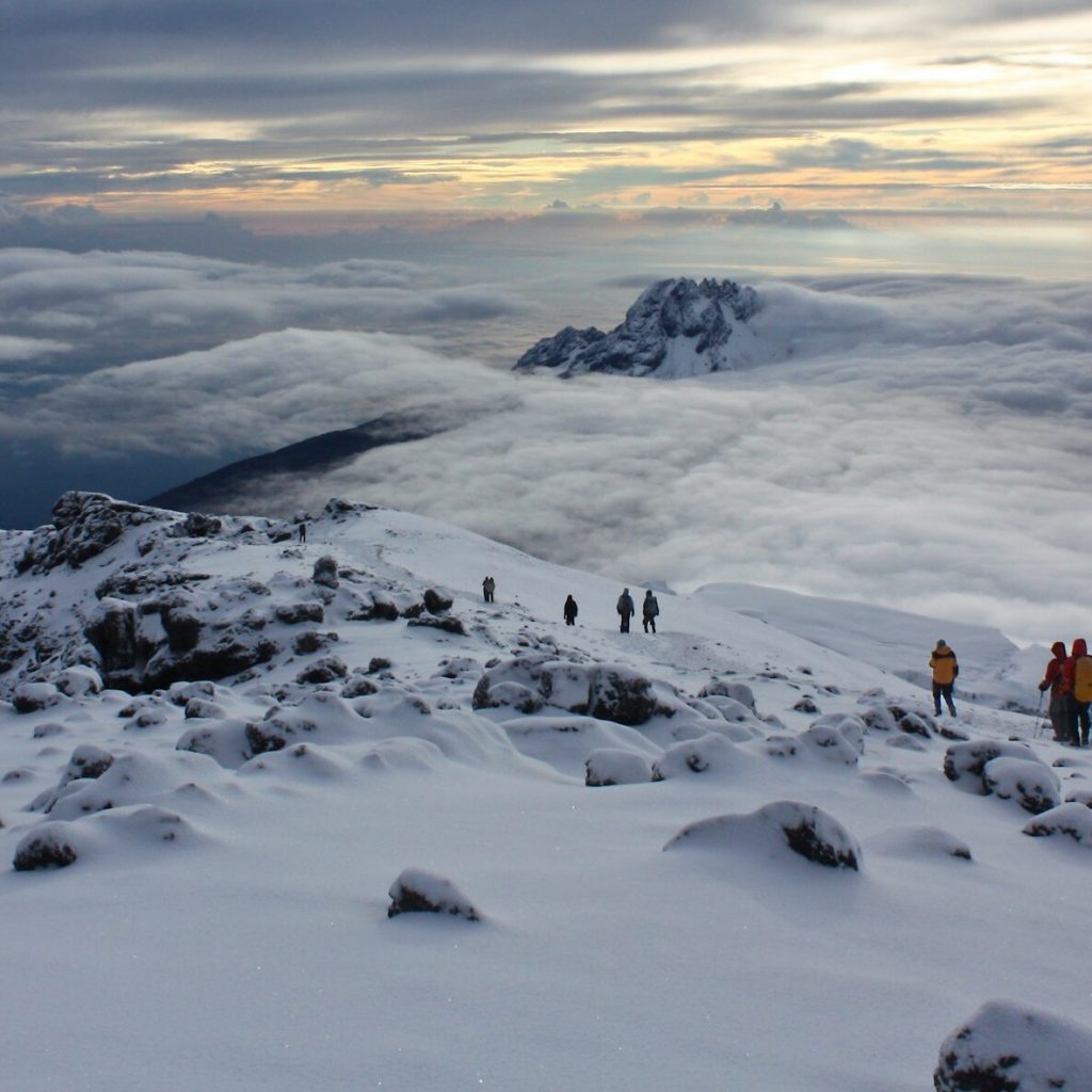Trekkers walking through snow at mountain summit in Mount Kilimanjaro National Park