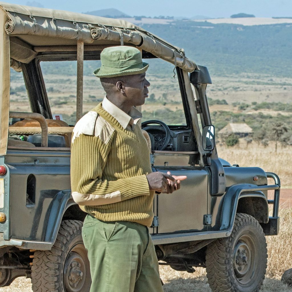 Safari guide in Kenya standing by 4x4 vehicle
