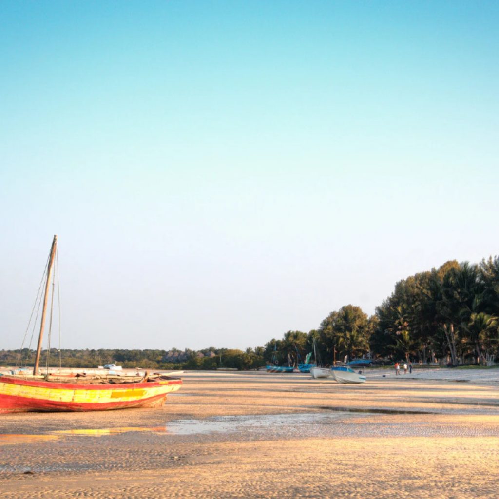 Yellow and orange boat adrifft on sand at low tide on Vilanculos Beach, Mozambique