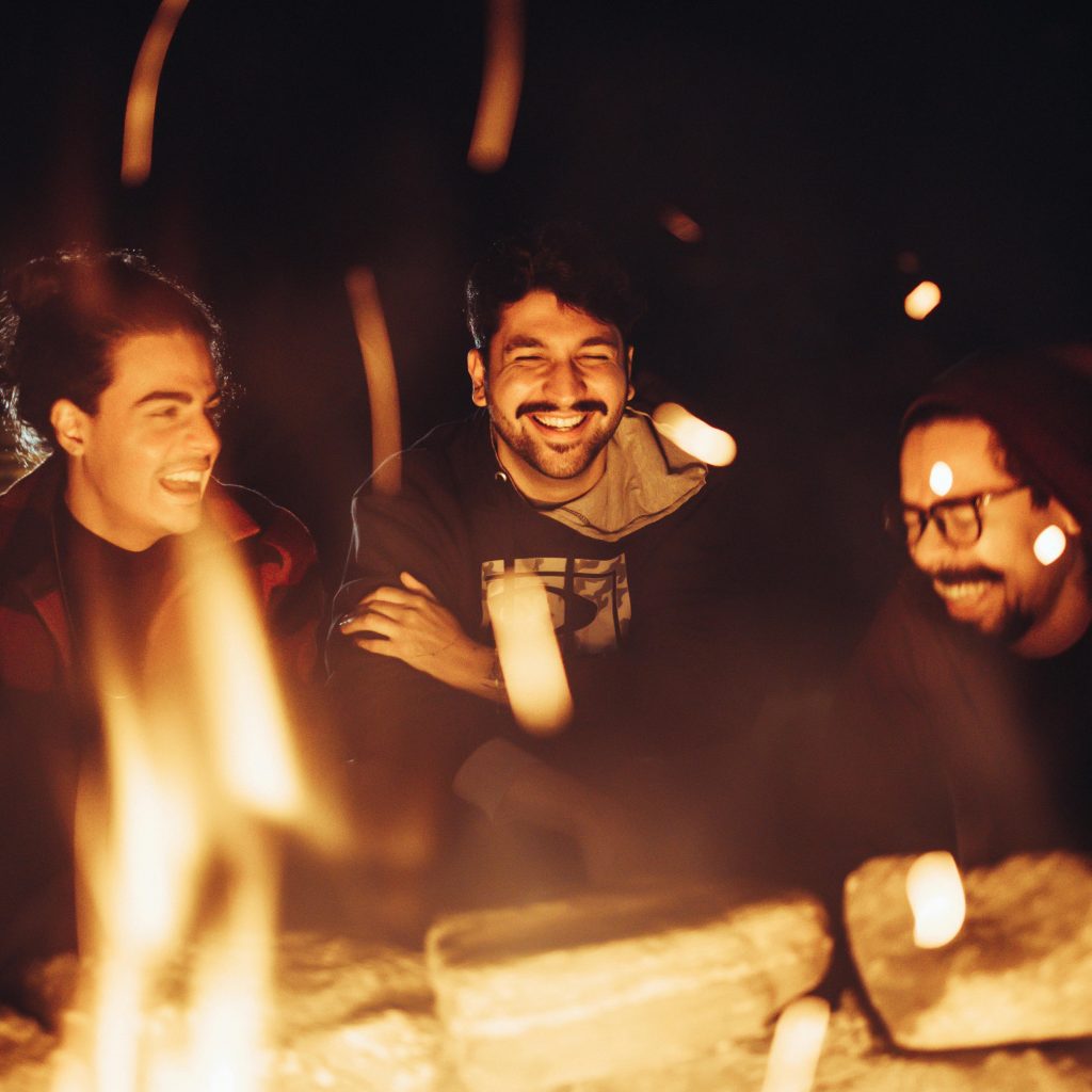 Young adults around a campfire, laughing and bonding, the big advantange of small group travel in Africa