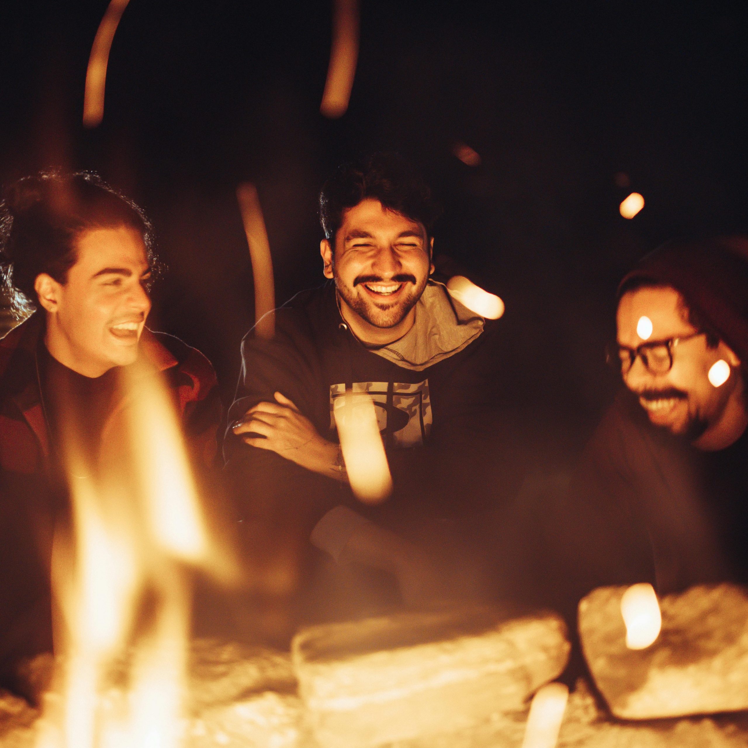 Young adults around a campfire, laughing and bonding, the big advantange of small group travel in Africa