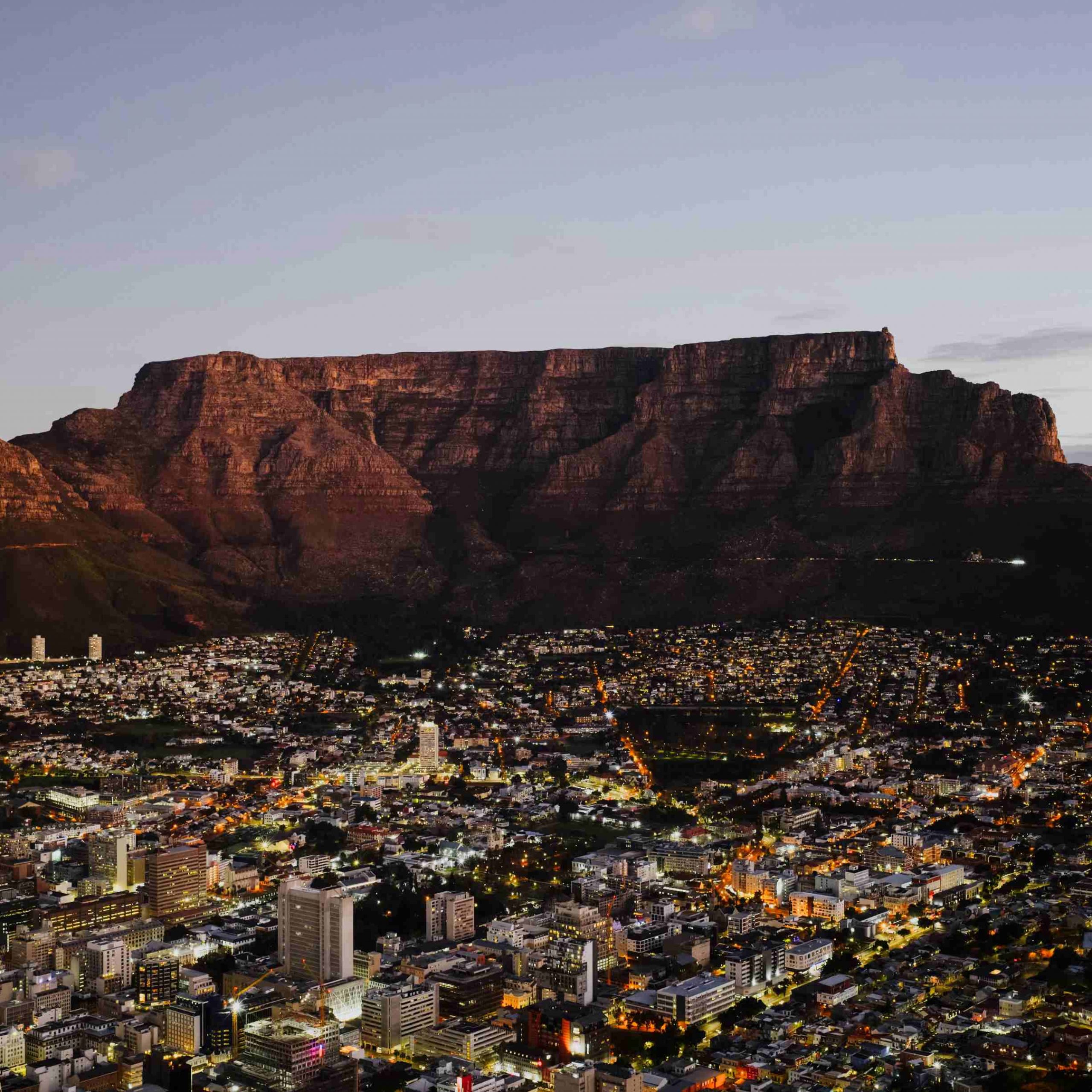 Aerial view of front face of Table Mountain with Cape Town city bowl below at twilight