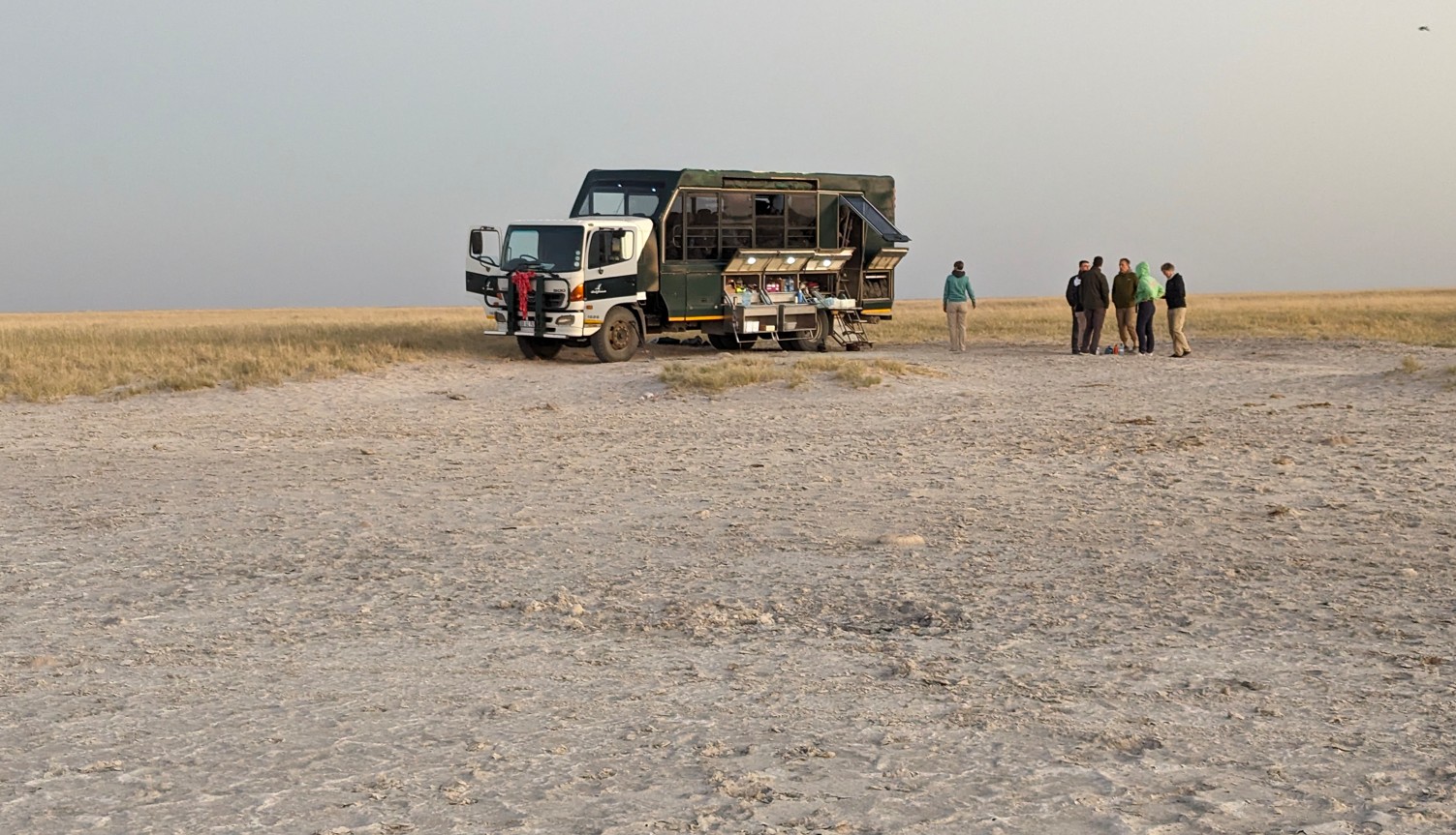 Overland Truck with guests standing and looking at the Pans in Botswana