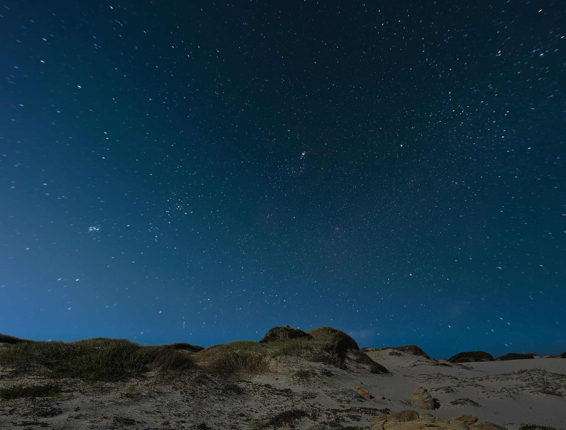 Sand dunes and rocks with starry night sky